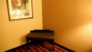 A hallway with a patterned carpet, a bench, and a framed artwork on the wall.