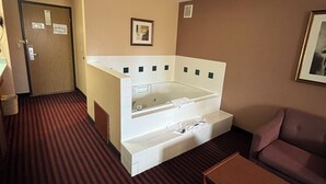 A hotel room with a large bathtub, a sofa, and a small table. - Americas Best Value Inn & Suites Forest Grove Hillsboro (Forest Grove)
