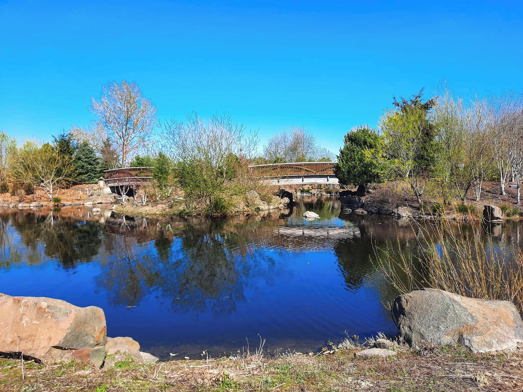 A tranquil riverside scene with a wooden bridge, a small boat, and a stone structure.