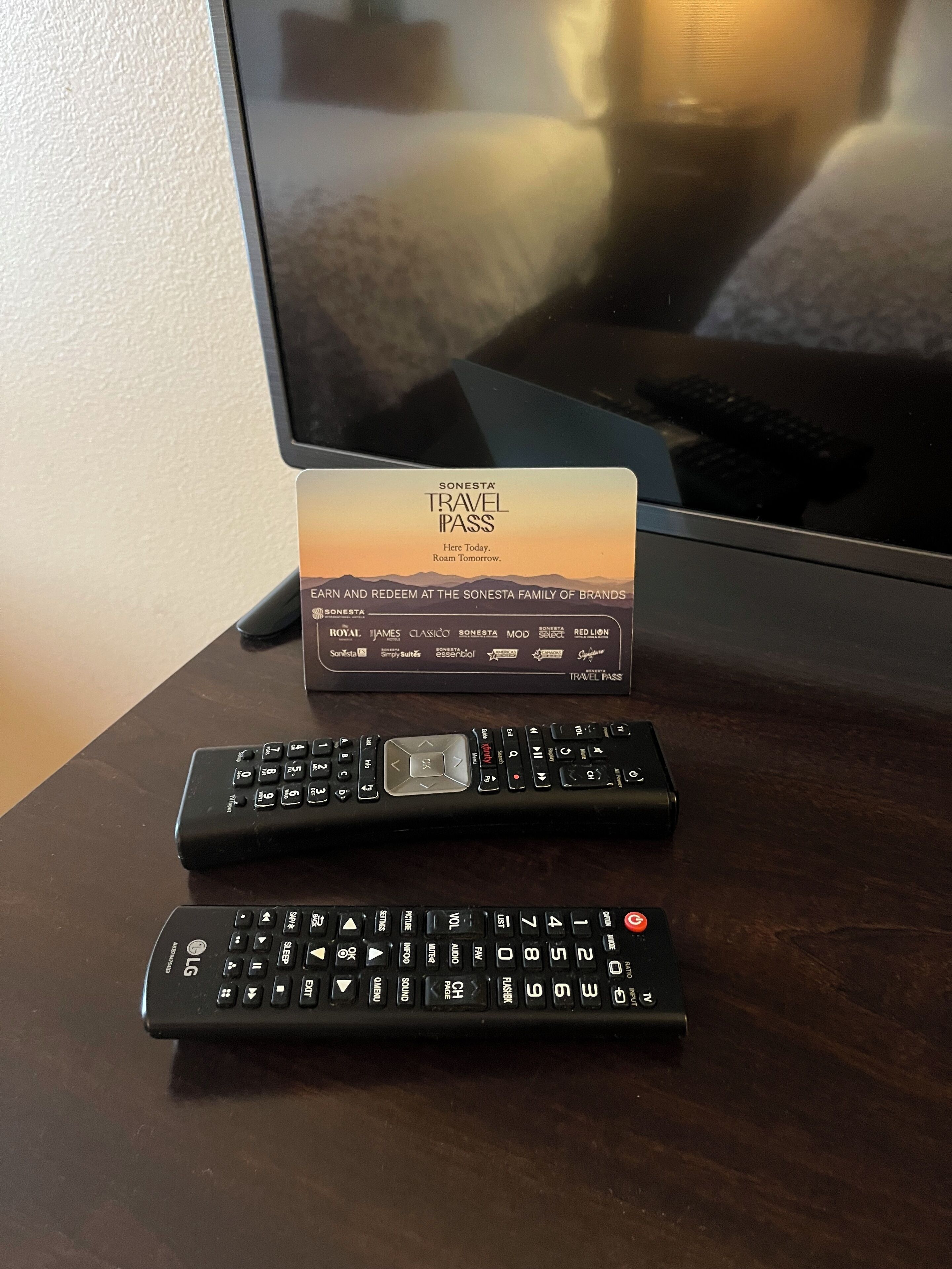 A travel pass and two remote controls on a wooden table.