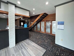 A reception area with a modern design, including a reception desk, a staircase, and a patterned carpet.