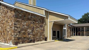 A building with a stone facade and a flat roof. - Motel 6 Ada, OK (Ada)