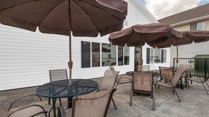 An outdoor patio with a round table and chairs, surrounded by brown umbrellas. - Days Inn by Wyndham Milan Sandusky South (Milan)