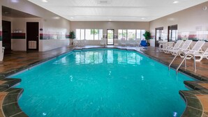 A large indoor swimming pool with clear blue water, surrounded by lounge chairs and a tiled deck. - Days Inn by Wyndham Milan Sandusky South (Milan)