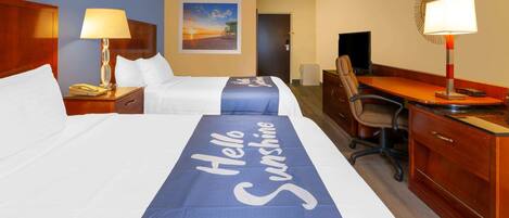 A hotel room with two beds, a desk, a chair, a lamp, and a painting on the wall.