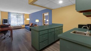 A compact hotel room with a kitchenette, a sofa, a desk, and a TV. - Days Inn by Wyndham Milan Sandusky South (Milan)