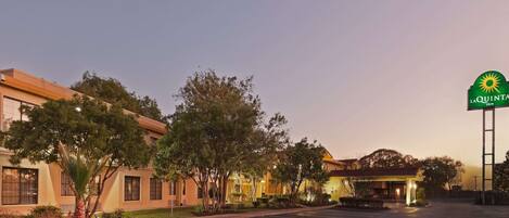 A hotel with a parking lot, a sign for 'La Quinta Inn & Suites', and a building with a yellow facade.