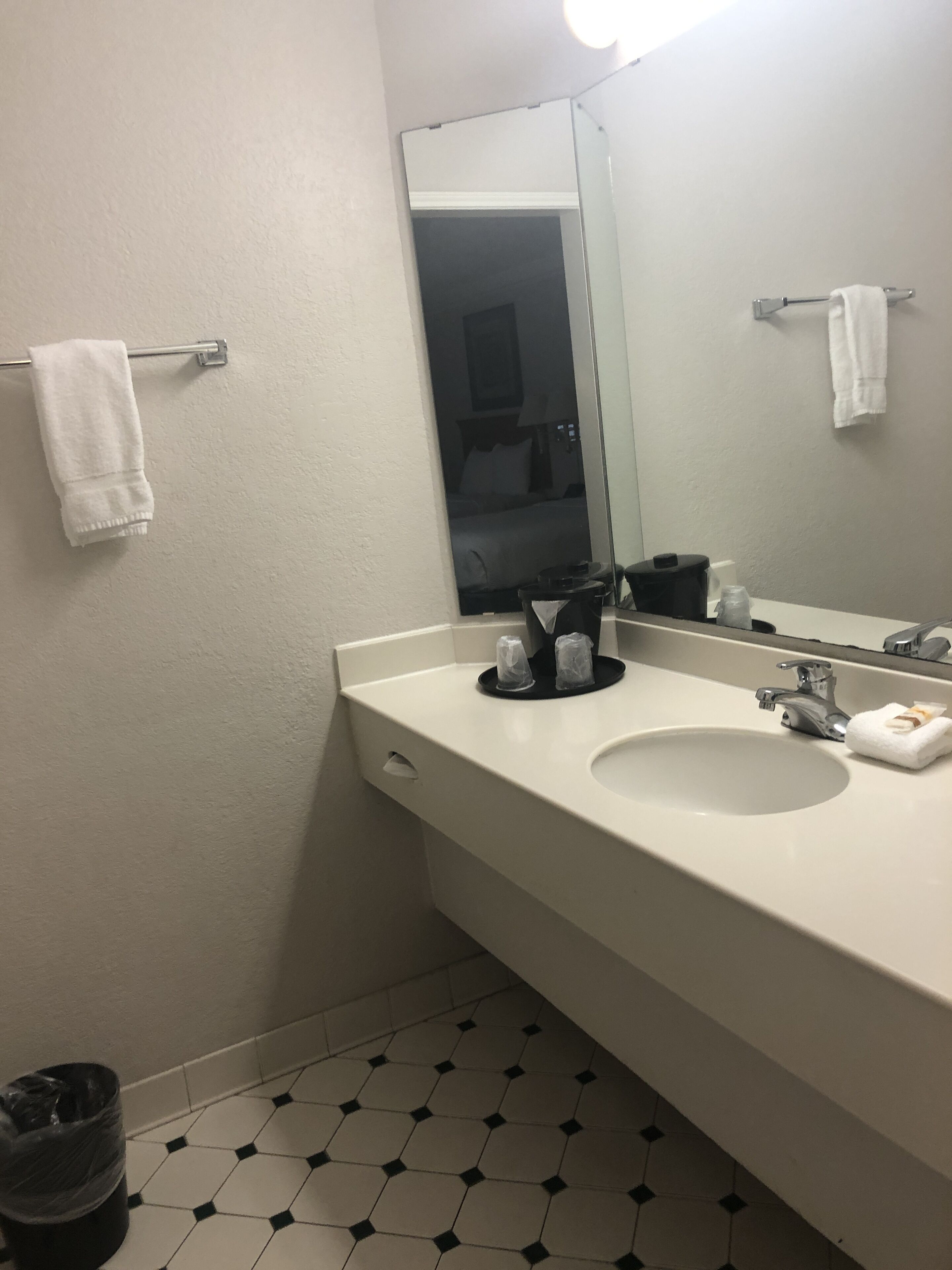 Une salle de bain avec un lavabo blanc, un miroir et une poubelle.