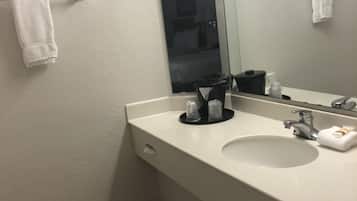Une salle de bain avec un lavabo blanc, un miroir et une poubelle.