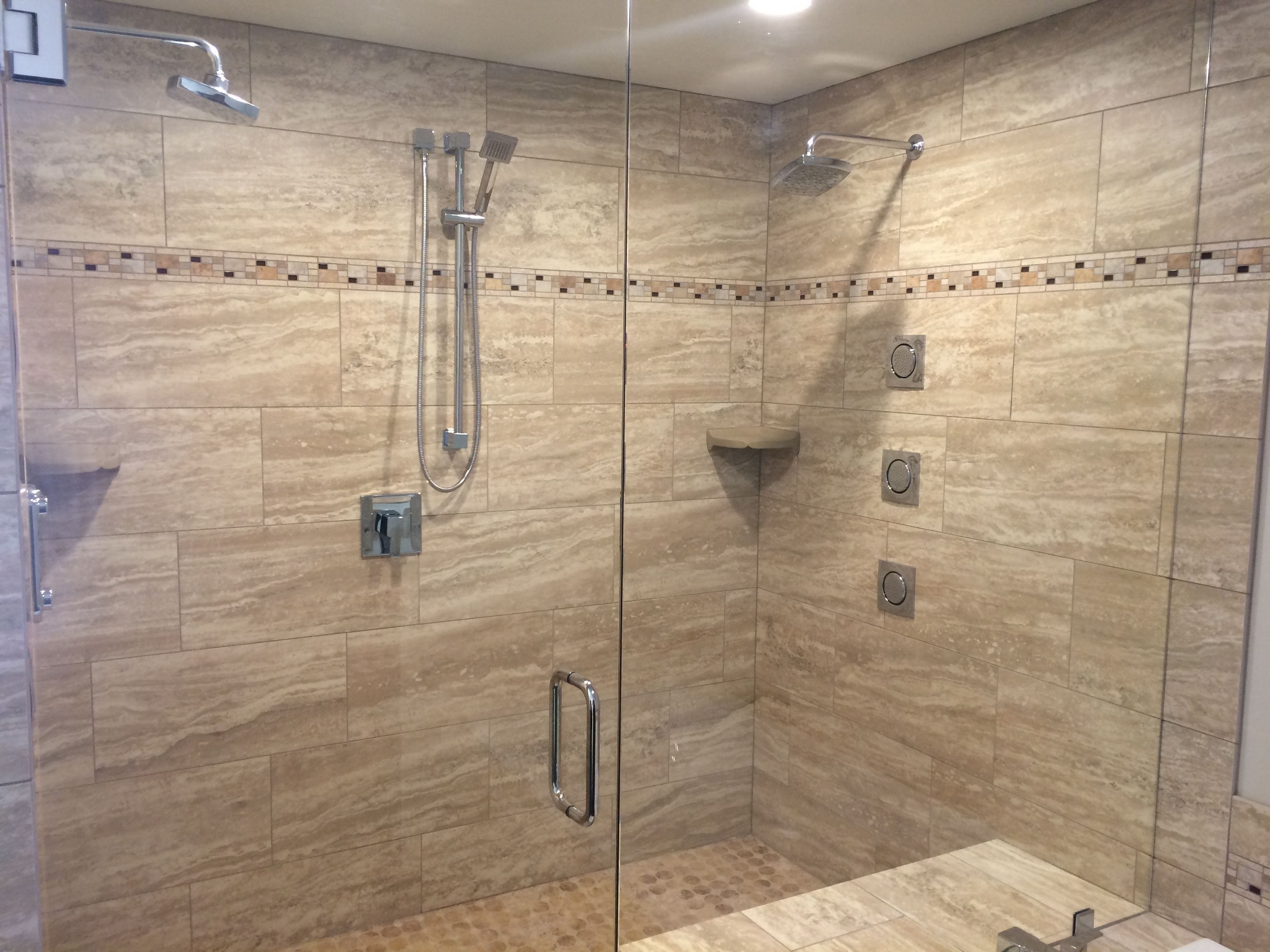 Una cabina doccia in vetro con diverse testine e un soffione a mano.