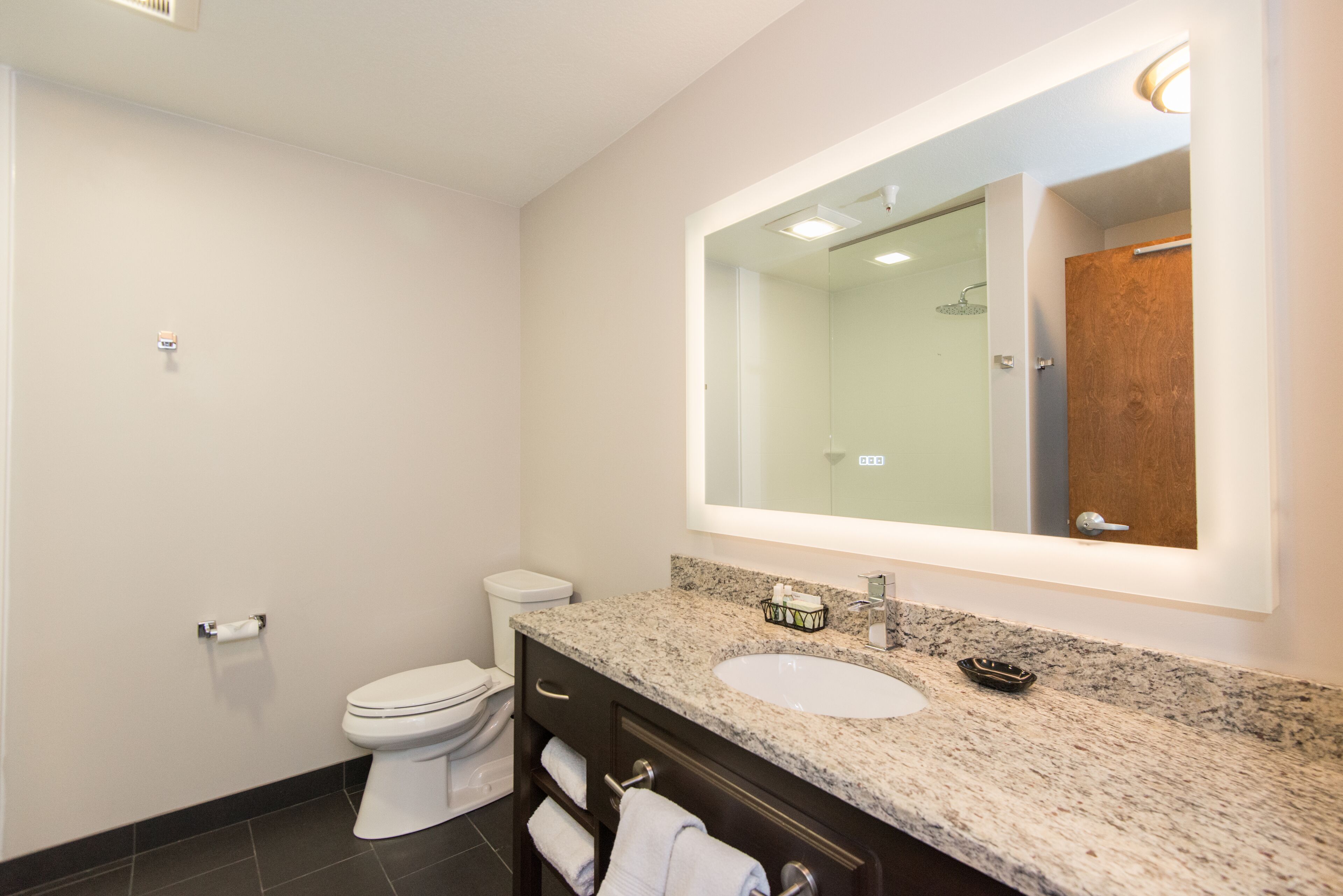 A modern bathroom with a white toilet, a sink with a mirror above it, and a towel rack.
