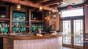 A bar area with a wooden counter, a stone wall, and a large window. - KwaTaqNuk Resort & Casino (Polson)