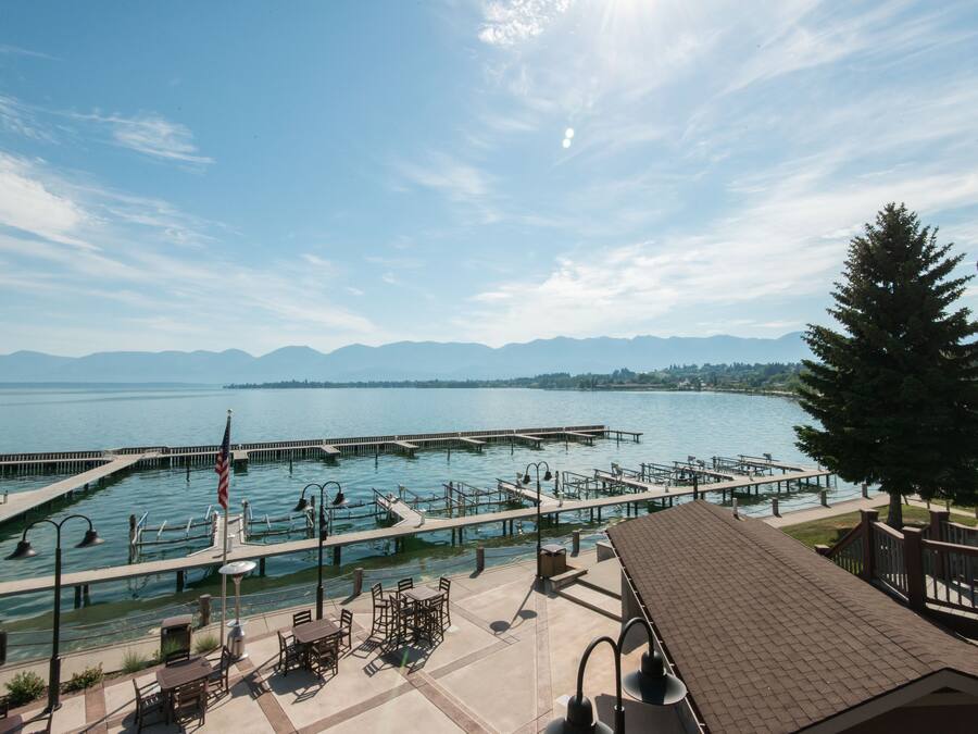 A waterfront patio with outdoor seating, a dock, and a view of a lake and mountains.