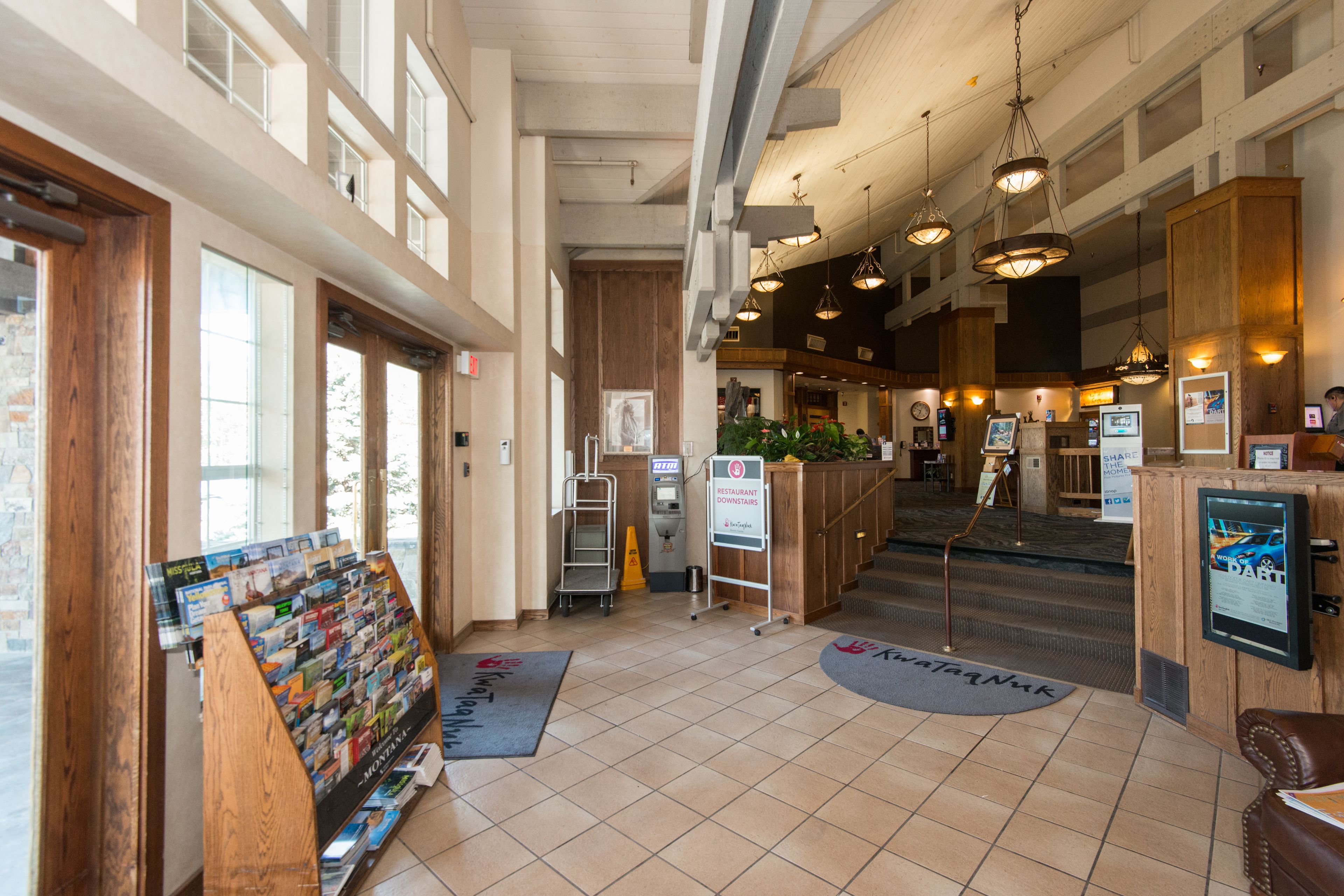 A spacious lobby with a reception desk, a magazine rack, and a staircase leading to upper floors.