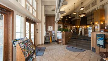 A spacious lobby with a reception desk, a magazine rack, and a staircase leading to upper floors.