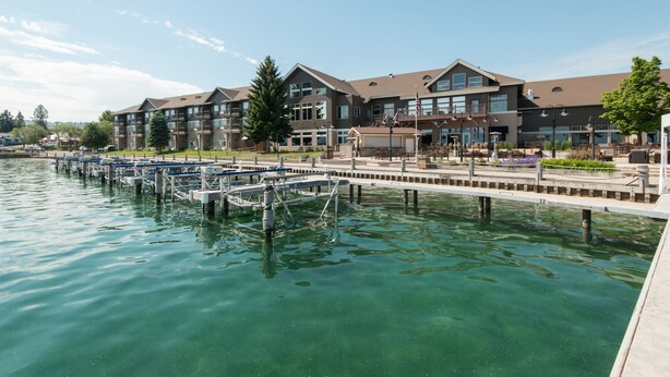 A waterfront hotel with multiple balconies, a dock with boats, and a clear view of the water. - KwaTaqNuk Resort & Casino (Polson)