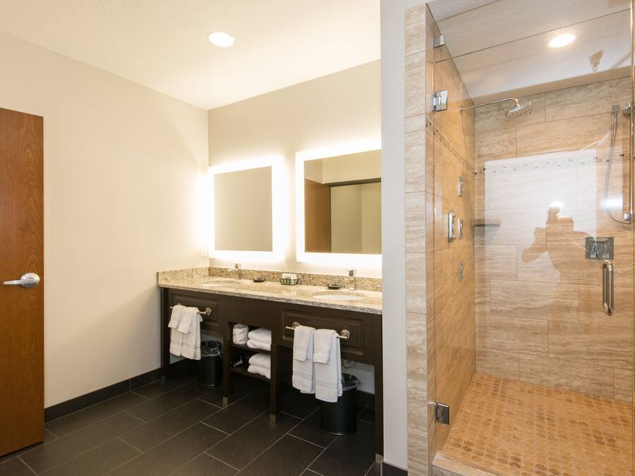 A modern bathroom with a glass-enclosed shower, a double sink vanity, and a large mirror.