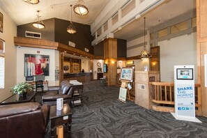 A lobby with leather seating, a reception desk, a clock, and a digital photo booth. - Kwataqnuk Resort (Polson)