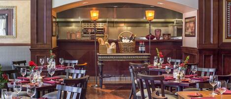 Un restaurant doté de nombreuses tables, de chaises et d’un bar central, avec une cuisine située à l’arrière.