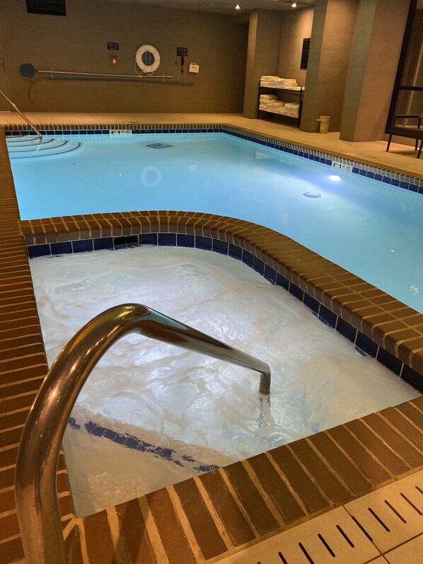 A swimming pool with a tiled edge, a metal handrail, and a lifebuoy on the wall.