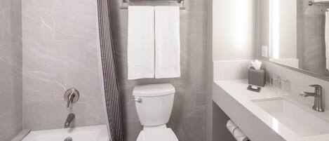 A modern bathroom with a bathtub, toilet, and shower.