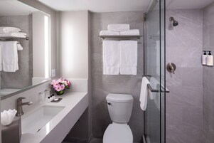 Un baño moderno con cabina de ducha de vidrio, inodoro blanco y tocador con lavabo y espejo.