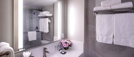 A modern bathroom with a large mirror, white sink, and a toilet.