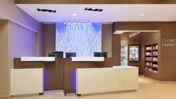 A reception area with a counter, a digital screen, and a market with shelves of products. - Fairfield Inn by Marriott Philadelphia Valley Forge (King of Prussia)