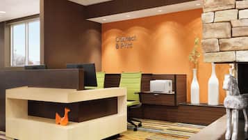 Un área de recepción moderna con una pared 'Connect & Print', un mostrador de recepción, zona de estar y una estatua decorativa de un caballo.