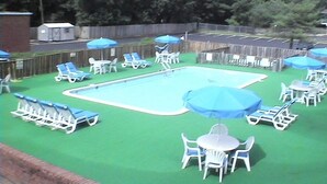 A backyard with a swimming pool, lounge chairs, and umbrellas. - Express Airport Inn (Sandston)