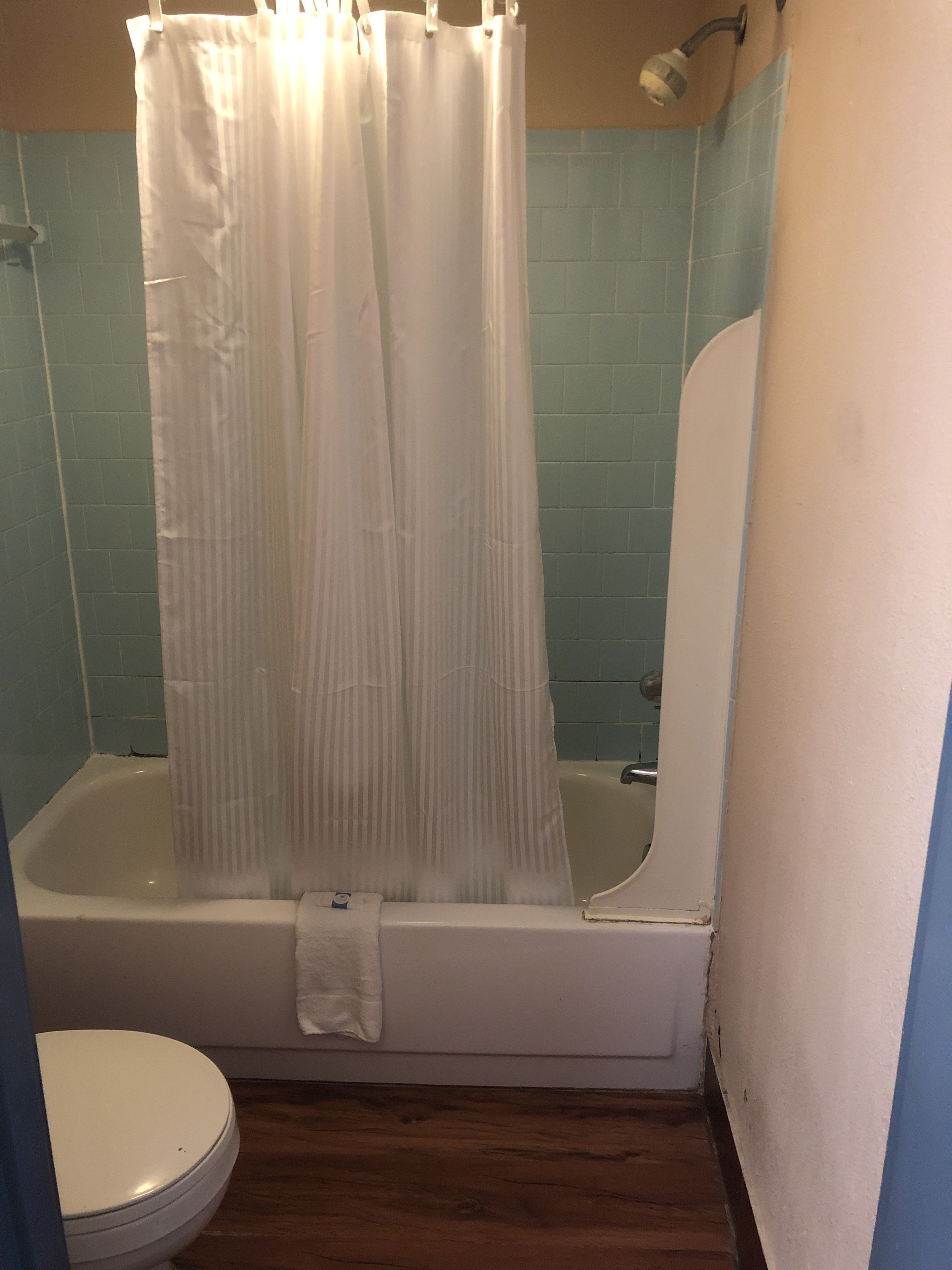 A bathroom with a bathtub, a shower curtain, and a toilet.