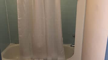 A bathroom with a bathtub, a shower curtain, and a toilet.