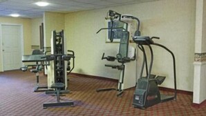 A fitness room with cardio and strength equipment, carpeted floor, and a door in the background. - Express Airport Inn (Sandston)
