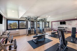 Et fitnesscenter med forskellig træningsudstyr, herunder håndvægte, bænkpres og et squat-stel.