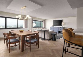 Een moderne hotelkamer met een zithoek, een bank, een televisie en uitzicht op de stad.