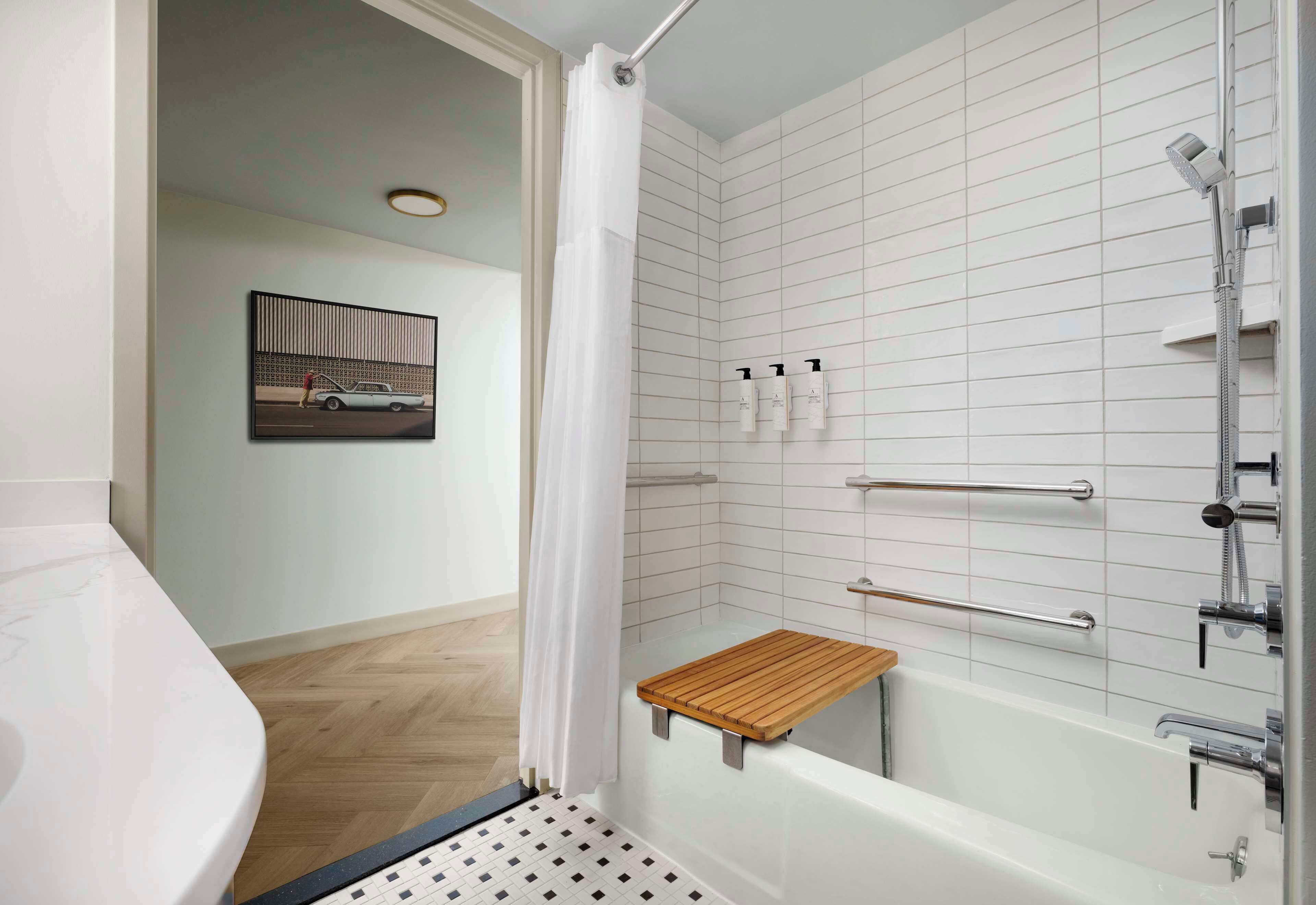 A modern bathroom with a bathtub, shower, and a wooden shelf.