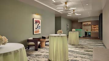 Un vestíbulo de hotel con mesas redondas, una zona de estar y un bar.
