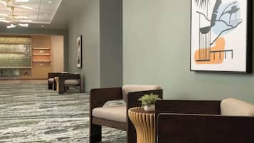 Un moderno vestíbulo de hotel con alfombra estampada, una mesa de recepción, zona de estar y un gran cuadro abstracto en la pared.