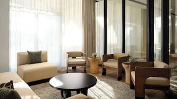 A modern living room with a sofa, chairs, a coffee table, and a patterned rug.