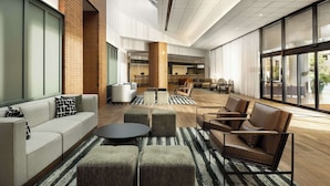 A spacious lobby with a modern design, featuring a large seating area with sofas and chairs, a coffee table, and a brick accent wall.