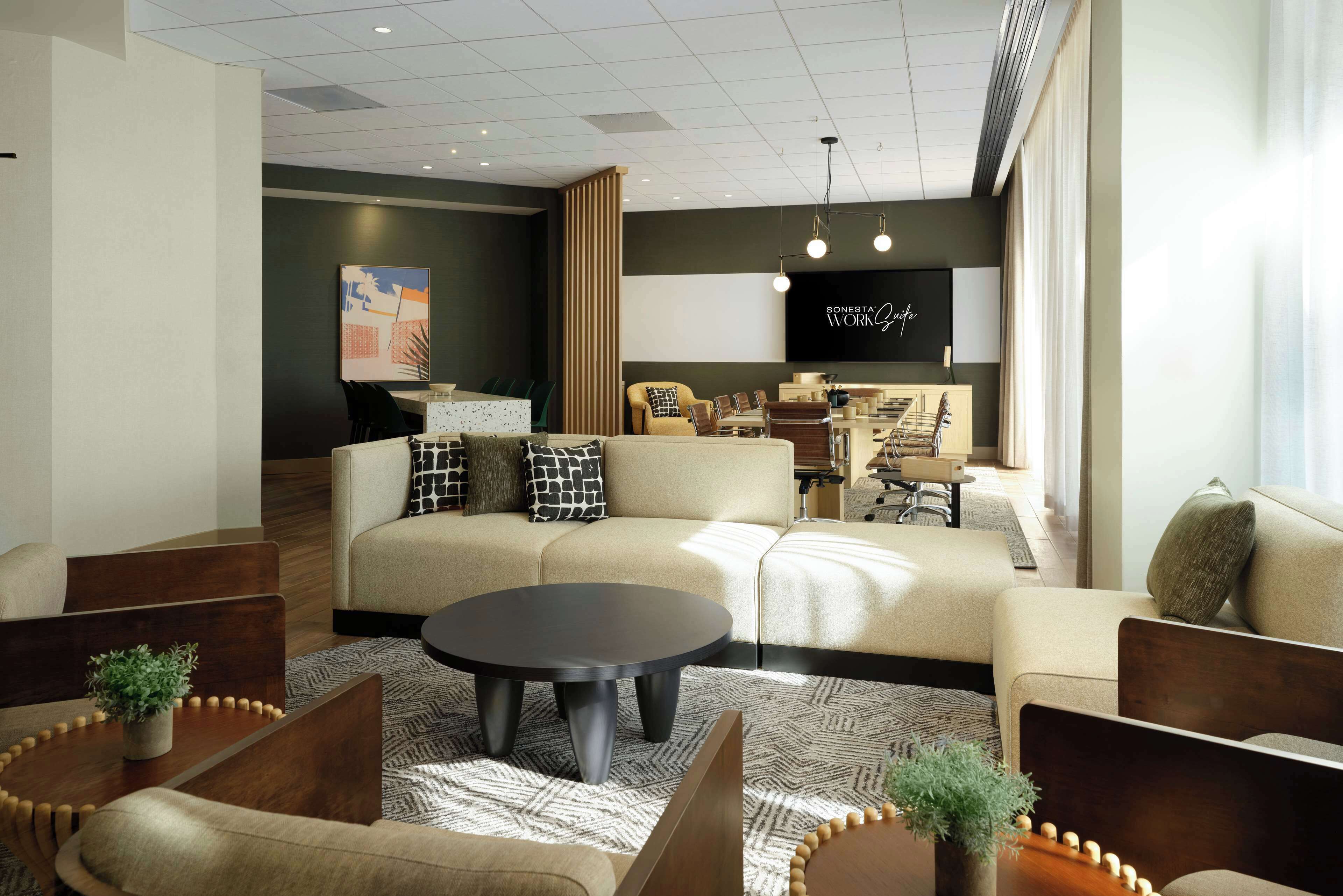 Una sala de estar moderna con un sofá, sillones, una mesa de centro y un televisor montado en la pared.