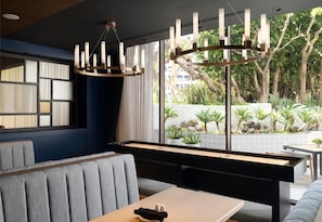 A modern interior with a pool table, seating area, and large windows offering a view of greenery. - Sonesta Los Angeles Airport LAX (Los Angeles)