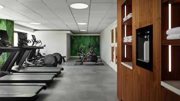 Ein Fitnessstudio mit Laufbändern, Ergometer und einer grünen Wand.