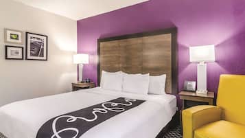 Ein Hotelzimmer mit einem großen Bett, zwei Nachttischen, einem Kopfteil und einem gelben Sessel.