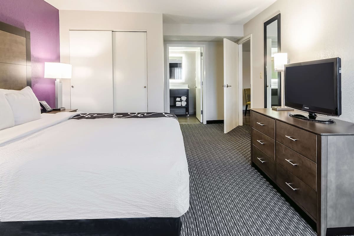 Een hotelkamer met een bed, een televisie, een kast en een badkamer, zichtbaar door een geopende deur.