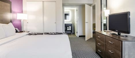 Ein Hotelzimmer mit Bett, Fernseher, Kommode und einem durchgegangenen Tür erkennbaren Badezimmer.