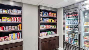Un espace dédié aux collations et aux boissons, avec des étagères remplies de divers en-cas et un réfrigérateur contenant une variété de boissons.
