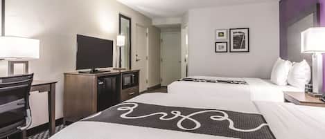 Una habitación de hotel con cama, escritorio, televisor y puerta.