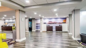A spacious lobby with a reception desk, a kitchen area, and a mural of a pier and Ferris wheel.
