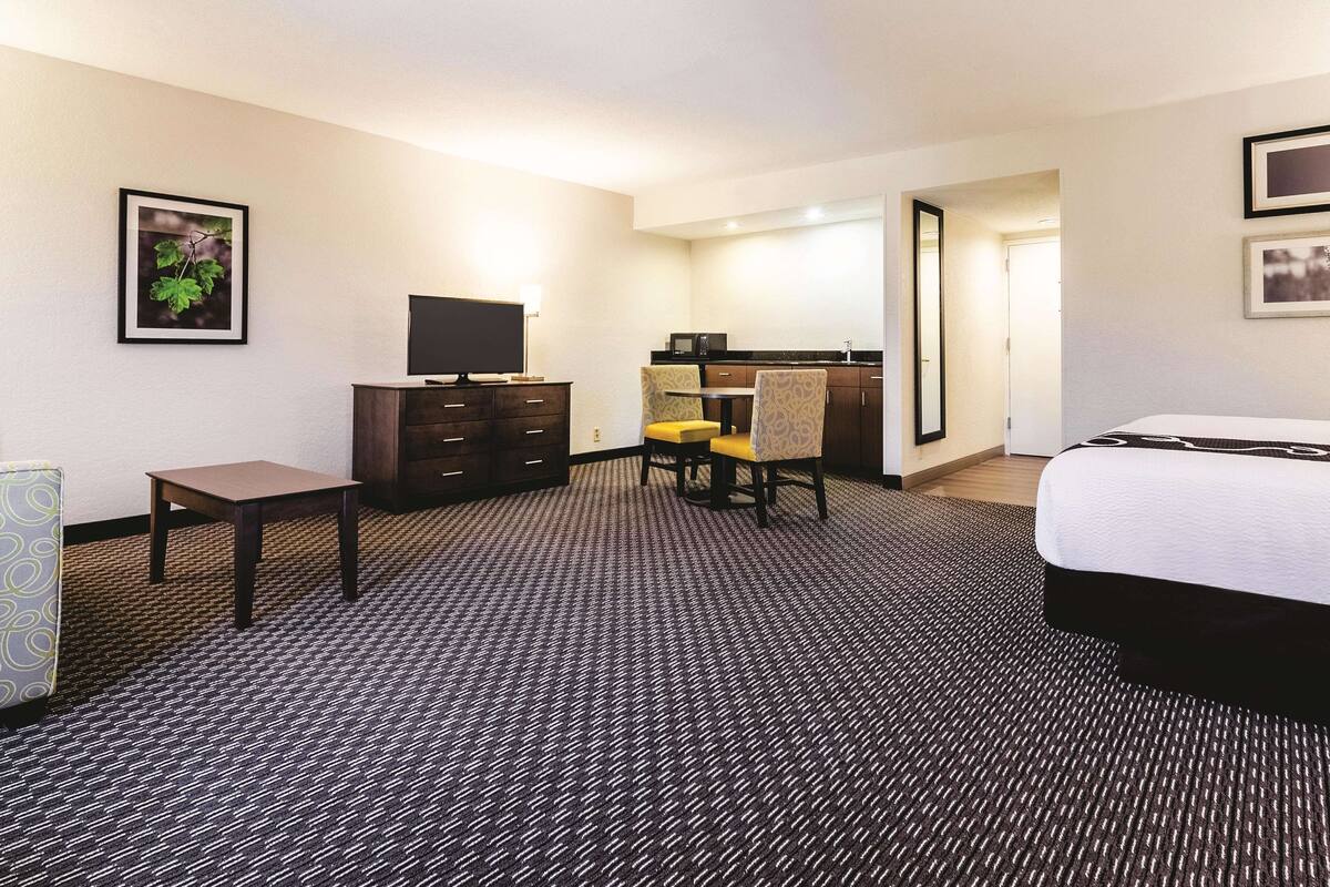Een hotelkamer met een bed, een bureau, een stoel, een dressoir en een televisie.